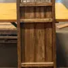 Rustic wooden screen with geometric lattice panel placed on a wooden cabinet atop a light wood table in a warehouse setting.