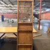 Tall wooden cabinet with a decorative lattice front, standing on a table in a large, empty industrial warehouse.
