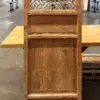 Tall wooden cabinet with a lattice-pattern upper panel and three paneled lower sections, in a warehouse setting.