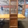 Tall antique wooden cabinet with a diamond lattice front panel on a workshop table in a warehouse setting.