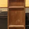 A weathered wooden cabinet with a lattice upper panel and two recessed lower panels, standing on a concrete floor in a workshop.