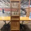 Tall wooden lattice screen with geometric cutouts mounted on a cabinet, centered on a long wooden table in a warehouse workshop.