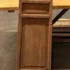 Tall wooden decorative screen with lattice panels between two wooden benches on a concrete floor.