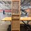 Tall wooden cabinet with decorative lattice front panels standing in an industrial warehouse setting