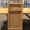 Tall rustic wooden cabinet with a woven lattice upper panel and solid lower sections, standing in a workshop.