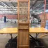 Tall wooden cabinet with a lattice door standing on a table in a spacious warehouse.