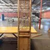 Tall weathered wooden lattice screen with geometric window-pane design standing on a table in an open industrial space.
