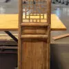Wooden decorative lattice screen or room divider mounted on a wooden cabinet in a warehouse setting, with tables in the background.