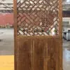 Wooden lattice panel with thick posts in a workshop, with brick walls and worktables visible in the background