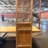 Tall wooden cabinet with a lattice-panel door standing in an empty warehouse space.