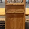 Tall wooden cabinet with a decorative lattice panel at the top, standing in a carpentry workshop.