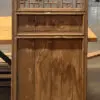 Wooden carved screen with geometric lattice top and solid lower panels, mounted on a wooden pedestal in an industrial workshop setting