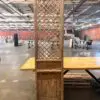 Tall wooden cabinet with a lattice panel standing on a yellow platform in a spacious workshop warehouse.