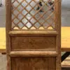 Wooden lattice screen with a carved panel at the bottom, placed on a wooden surface inside a workshop or showroom.