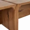 Close-up of a wooden table corner where the leg meets the apron, showing a rounded, hand-cut joint and visible wood grain.